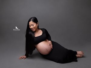 Graceful reclining maternity pose in a black studio gown, artistic pregnancy photography by Precious Pictures, Rabat, Malta.