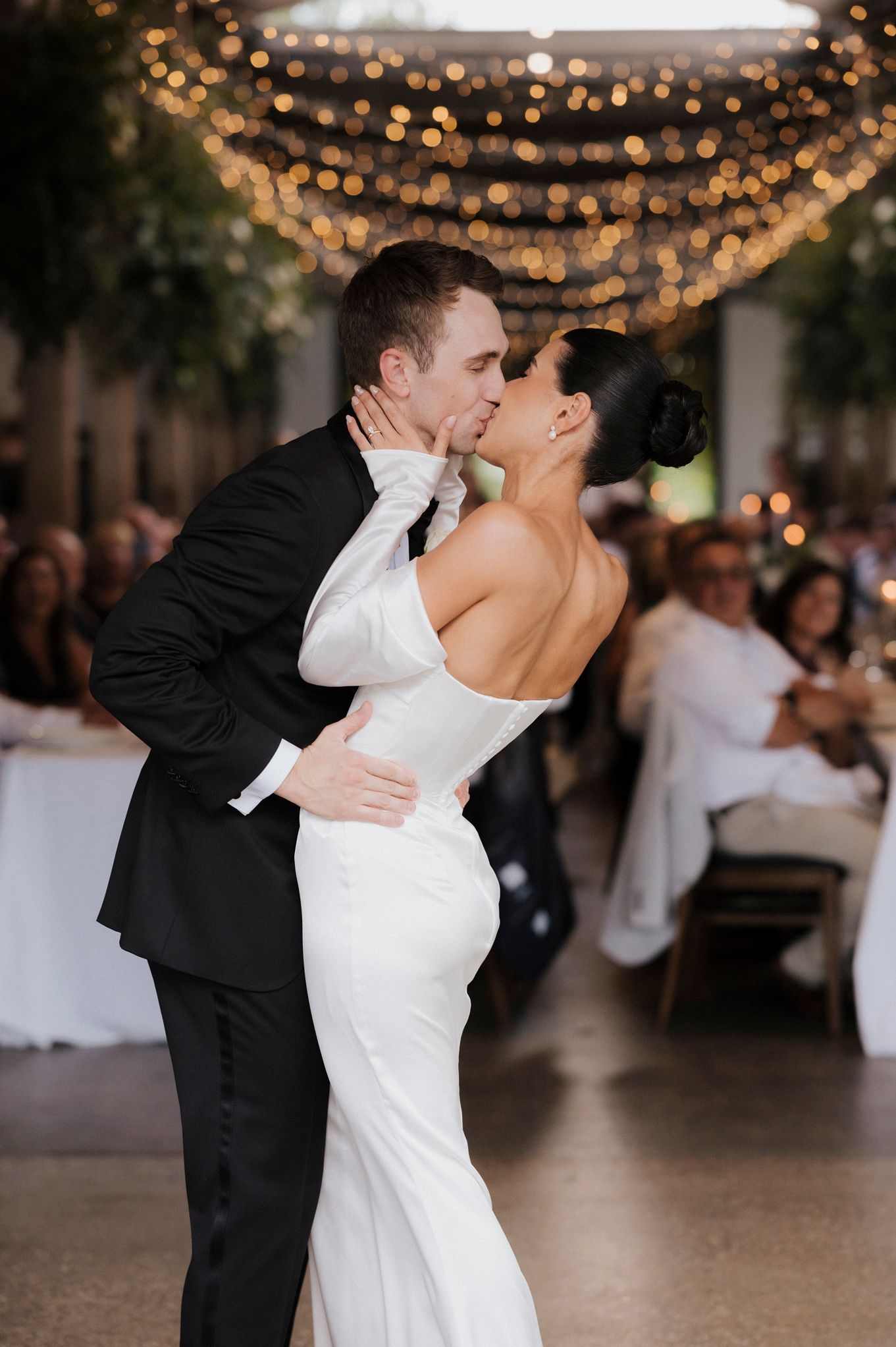 Elegant first dance moment under twinkling lights at wedding reception.