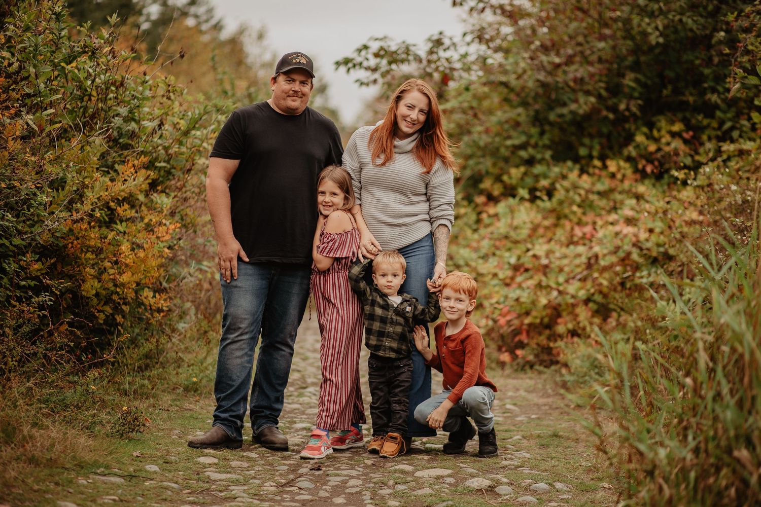 Family walking together on nature trail during autumn photo session.
