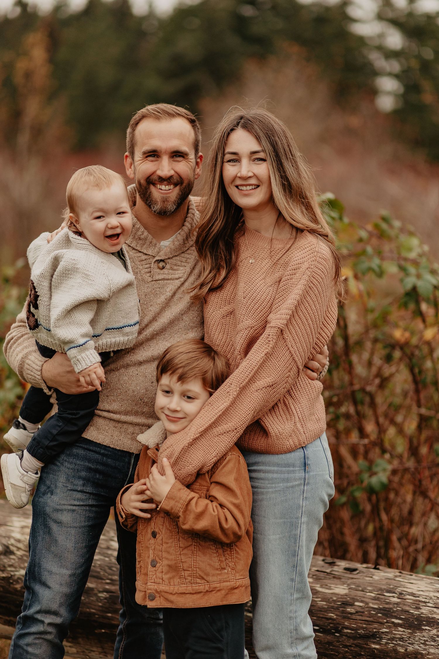 Family in cozy sweaters shares warm moments together during fall photo session.