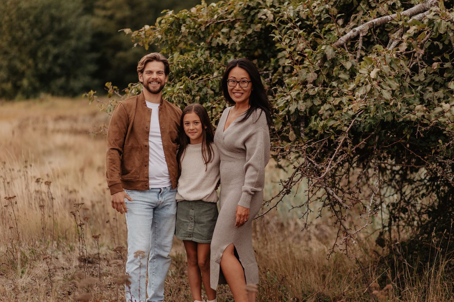 Couples pose casually in denim and neutral tones during outdoor photo session.