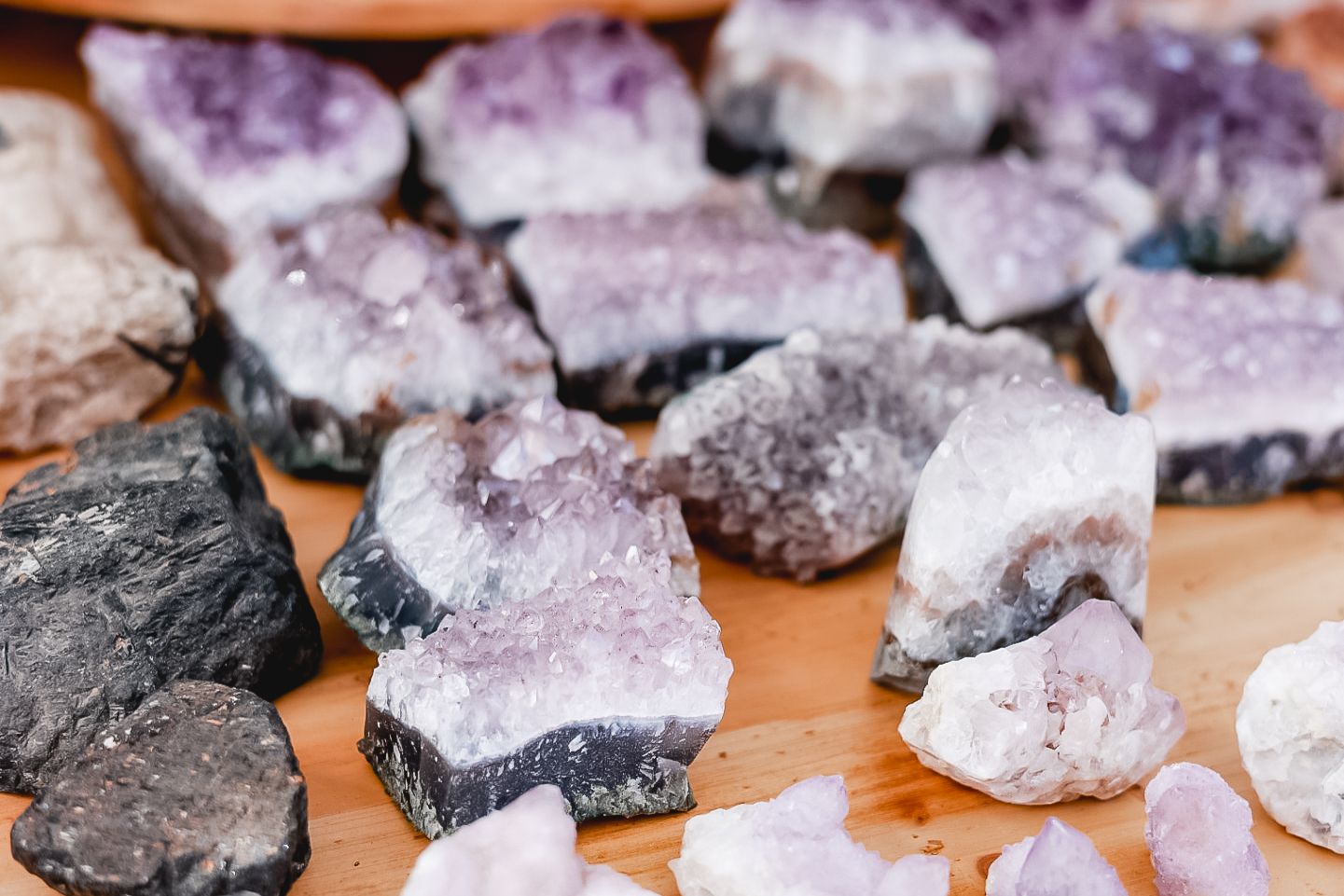 Collection of raw amethyst crystal clusters displayed on orange surface.