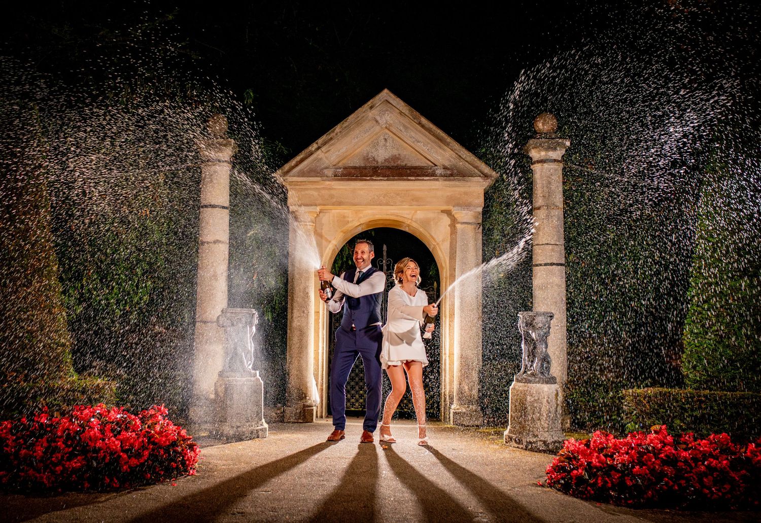 Elegant stone archway decorated with flowers creates romantic wedding venue at night.