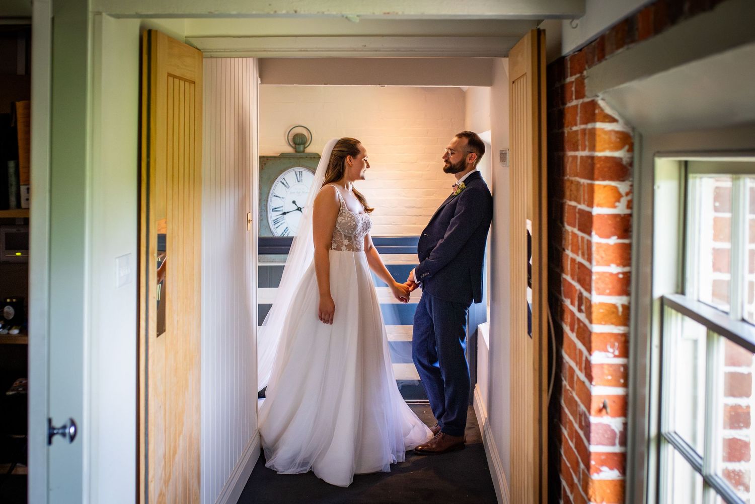 Bride and groom hold hands in a charming doorway, exchanging loving glances on their wedding day.
