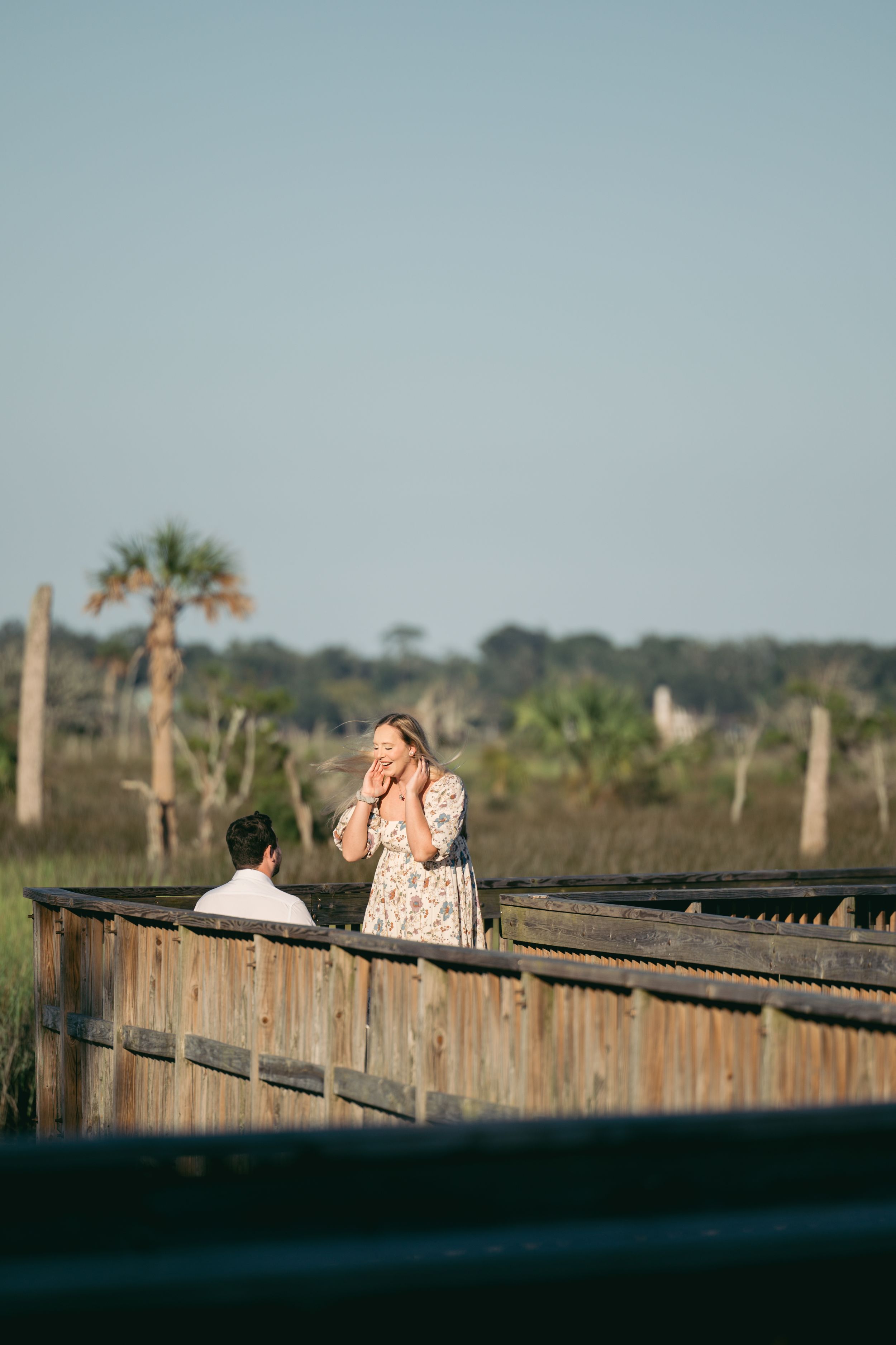 Couple sharing a romantic moment on a wooden bridge at sunset.