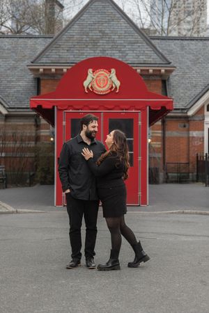 Couple sharing a romantic moment in front of a red-roofed building.