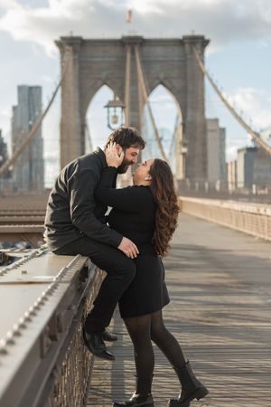 Romantic couple sharing a dip kiss on the iconic Brooklyn Bridge.