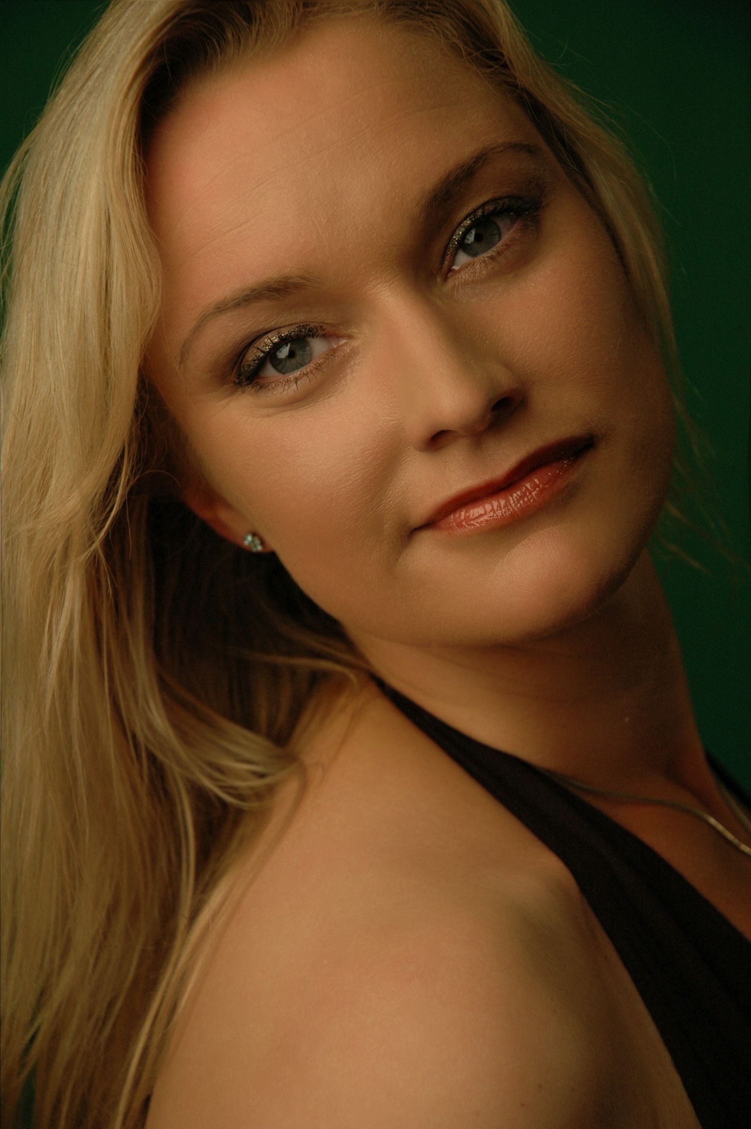 Studio portrait with dramatic green backdrop showcasing elegant beauty and classic glamour.