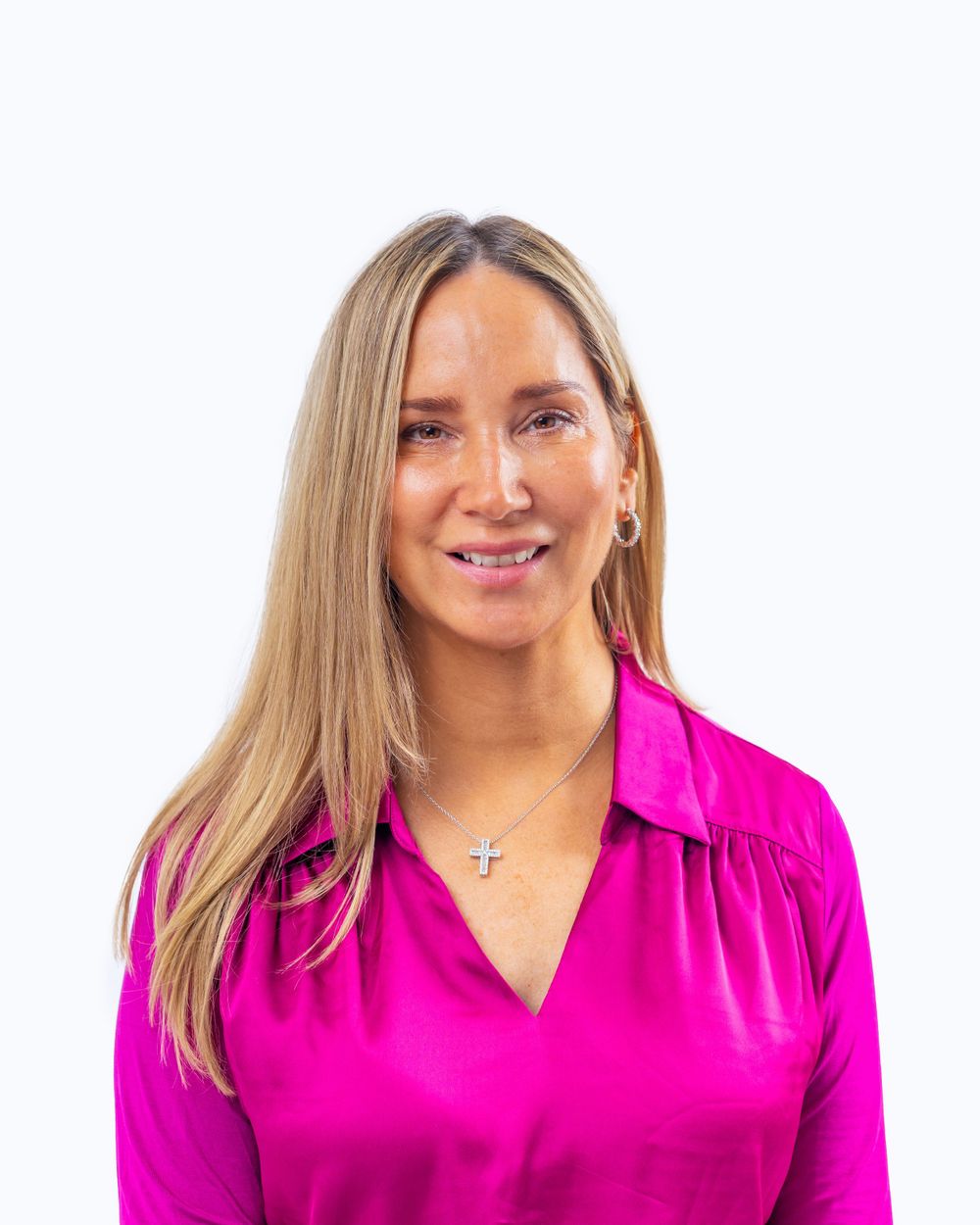 Professional headshot of a person with long blonde hair wearing a bright pink blouse against a white background.