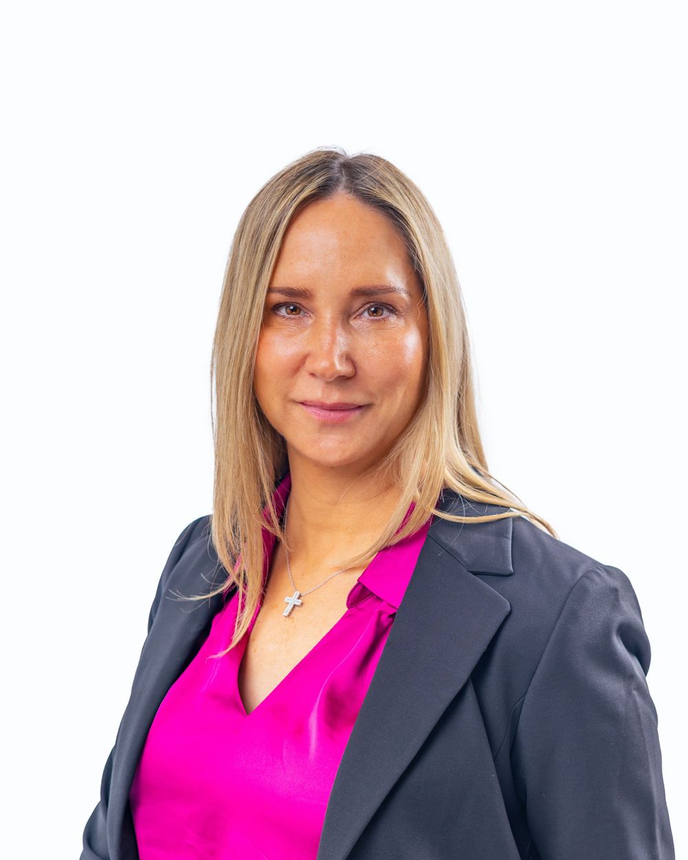 Professional portrait of a person in a black blazer and bright pink blouse against a white background.