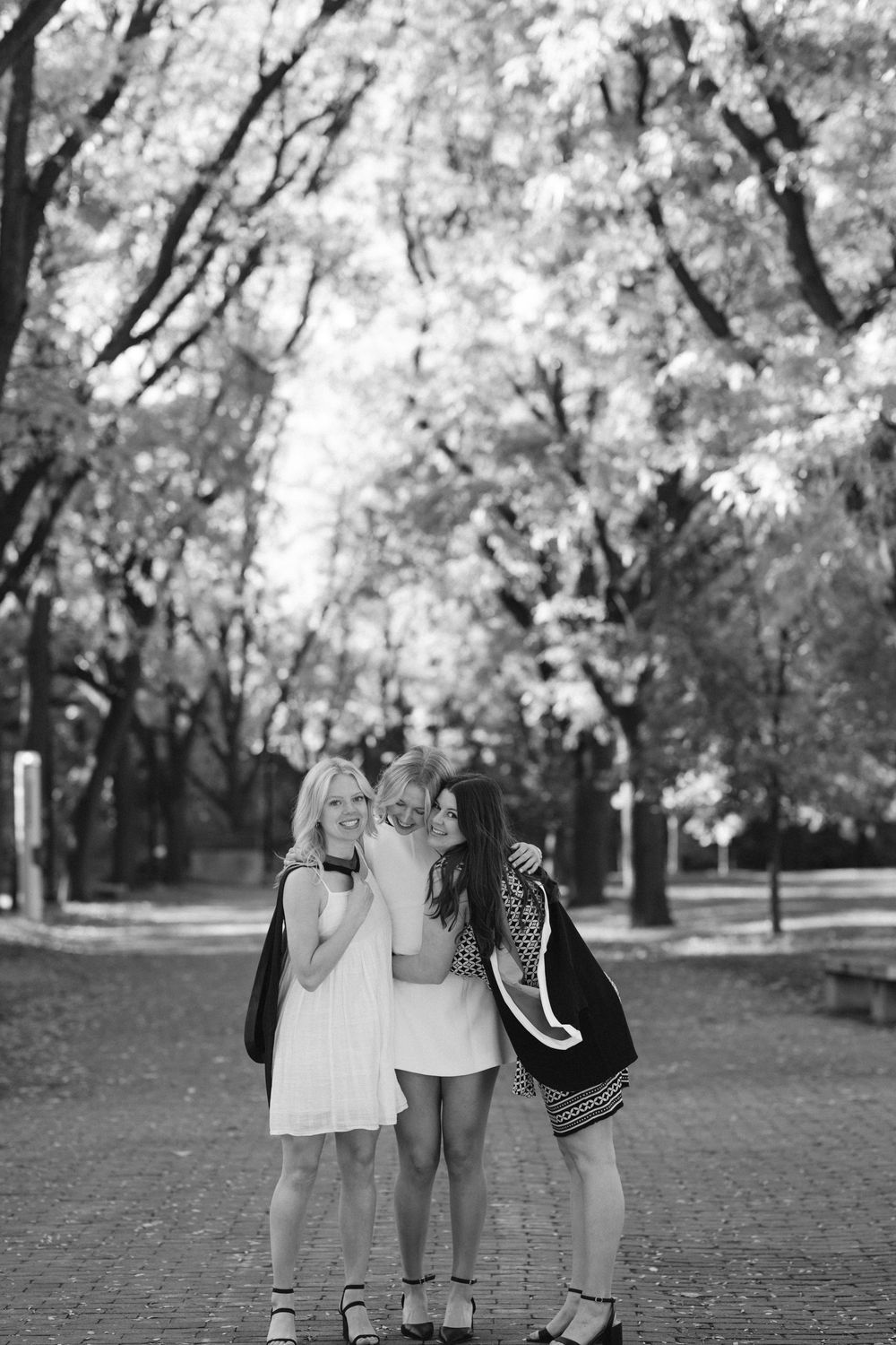 Four people walking together in a park with autumn trees in black and white photography.