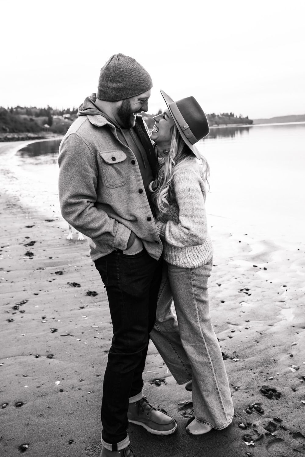 A couple sharing an intimate moment on a rocky beach during an overcast day.