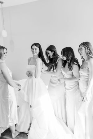 A candid black and white photo of bridesmaids sharing a joyful moment while getting ready.