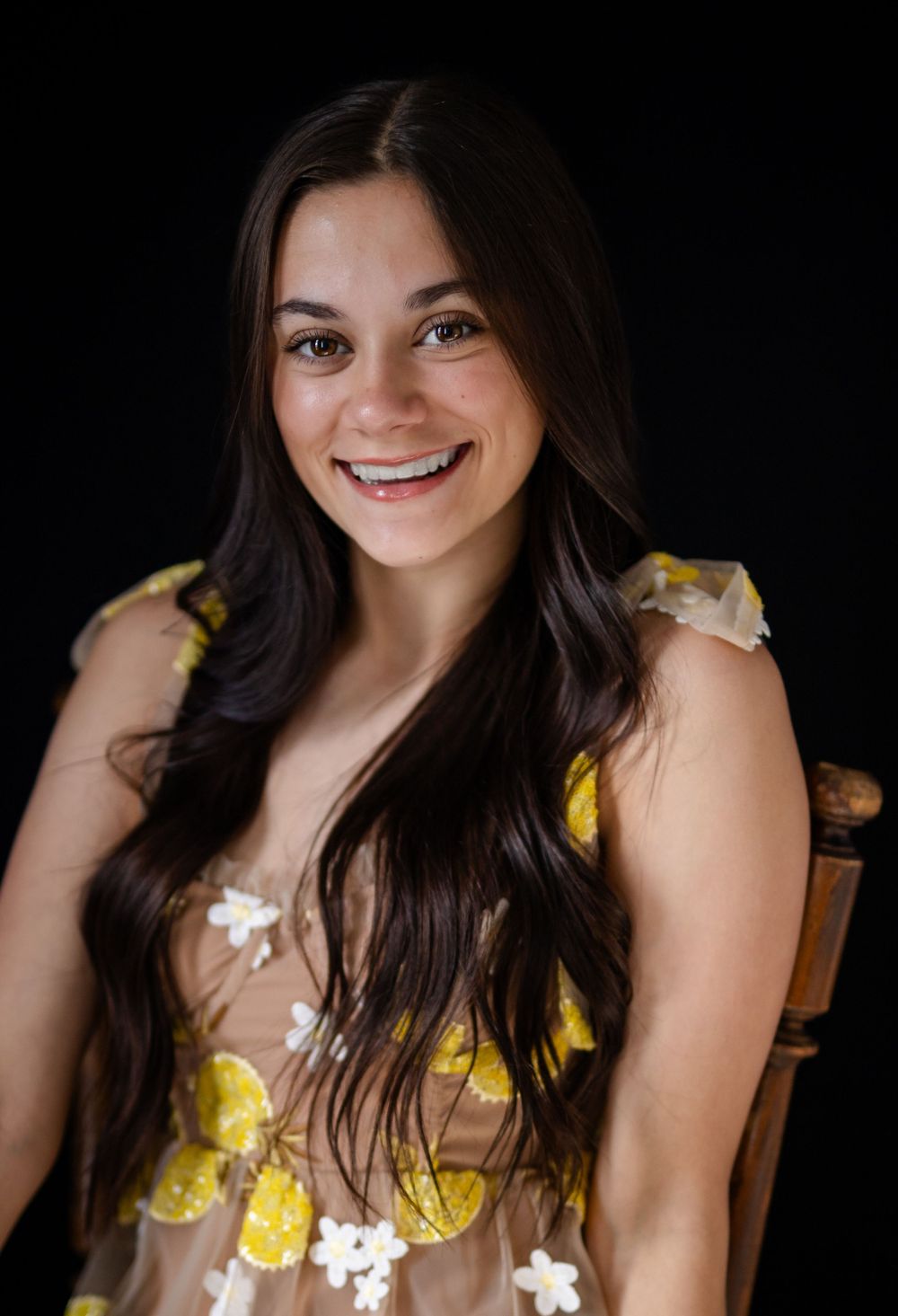 High school senior girl in a yellow floral dress on a dark studio backdrop in Mountain Home, Arkansas