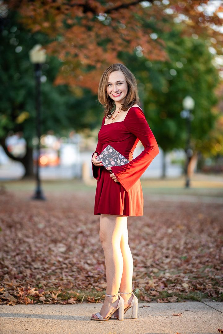 High school senior girl in a red dress among autumn trees during a senior session in Harrison, Arkansas