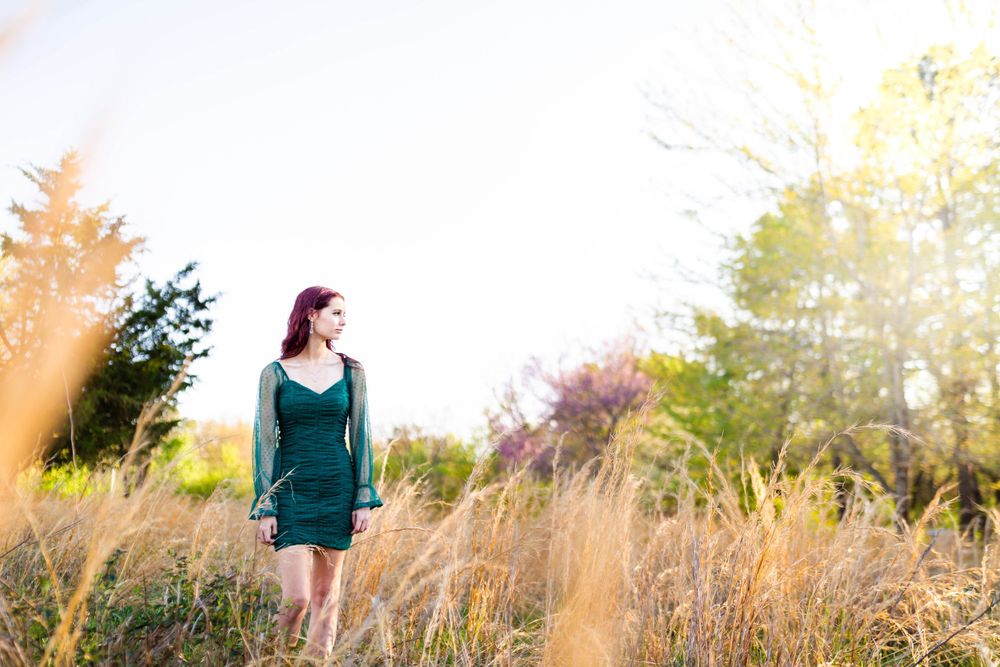 High school senior girl in a green dress in a sunlit field during an outdoor senior session in Mountain Home, Arkansas