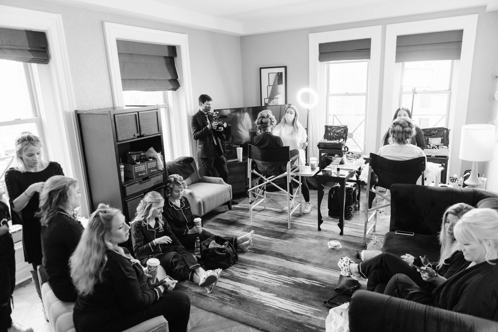 A black and white photograph of a group of people getting ready in a hotel suite
