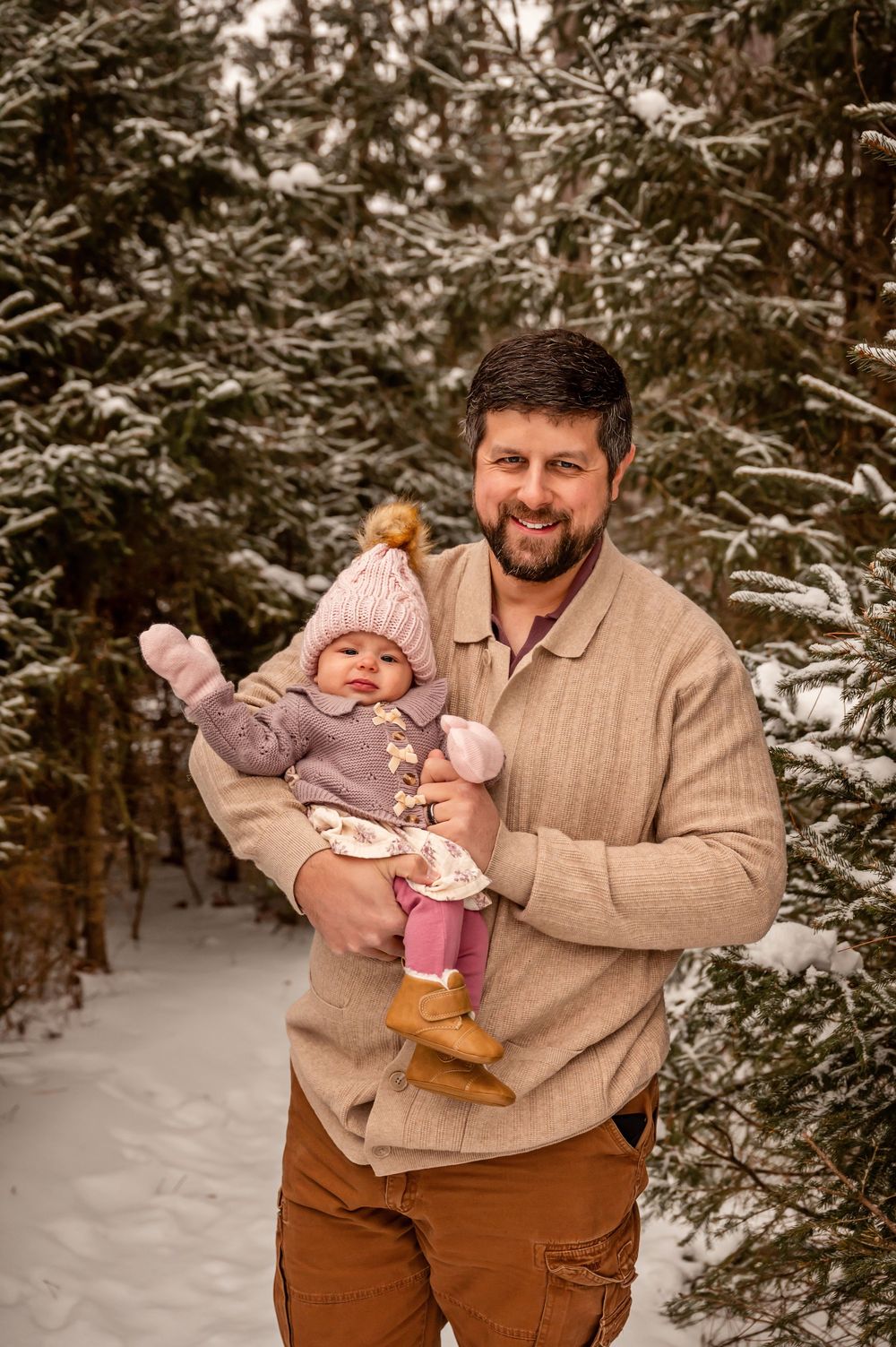 A series of snowy winter photos showing a person in a beige sweater holding a small child in brown and pink winter clothes.