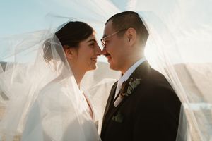 bride and groom kissing under vail