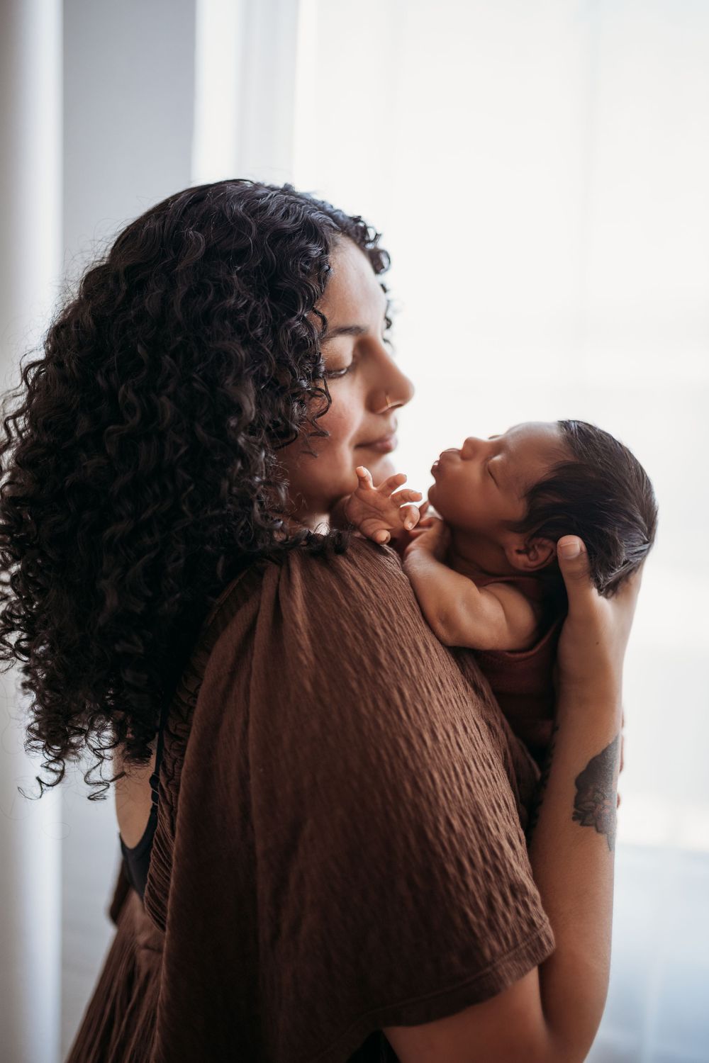 mother holding newborn while newborn puckers up looking at the mother.