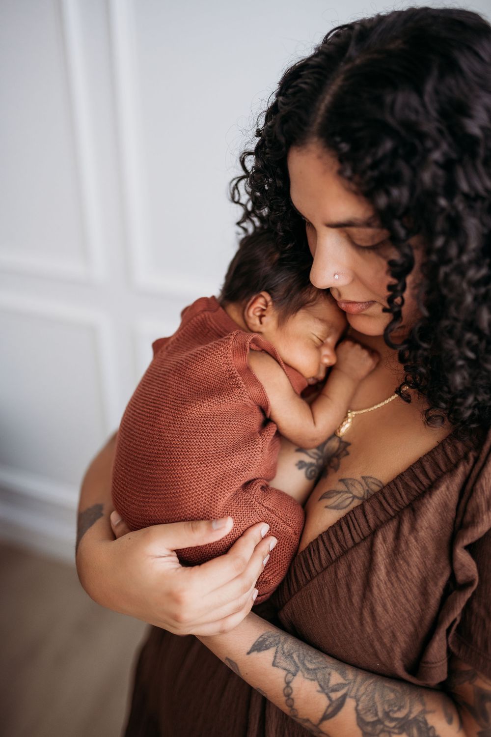 mother holding newborn to her chest with eyes closed.