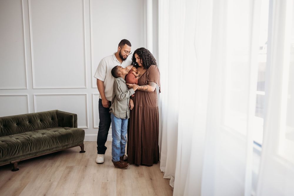 family embracing near a window wall with green sofa on the side