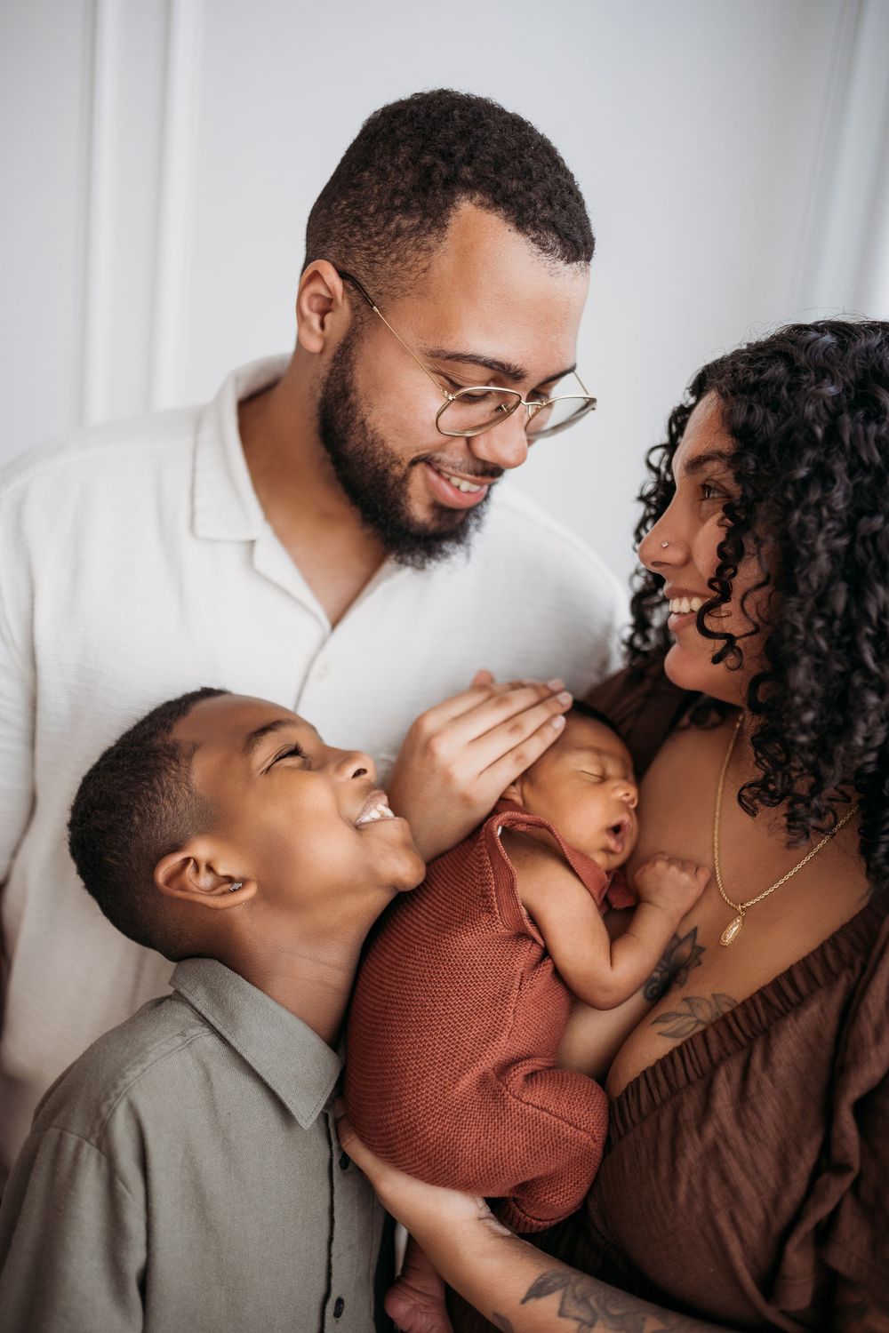 mother embracing newborn with father and sun surrounding them smiling at each other.