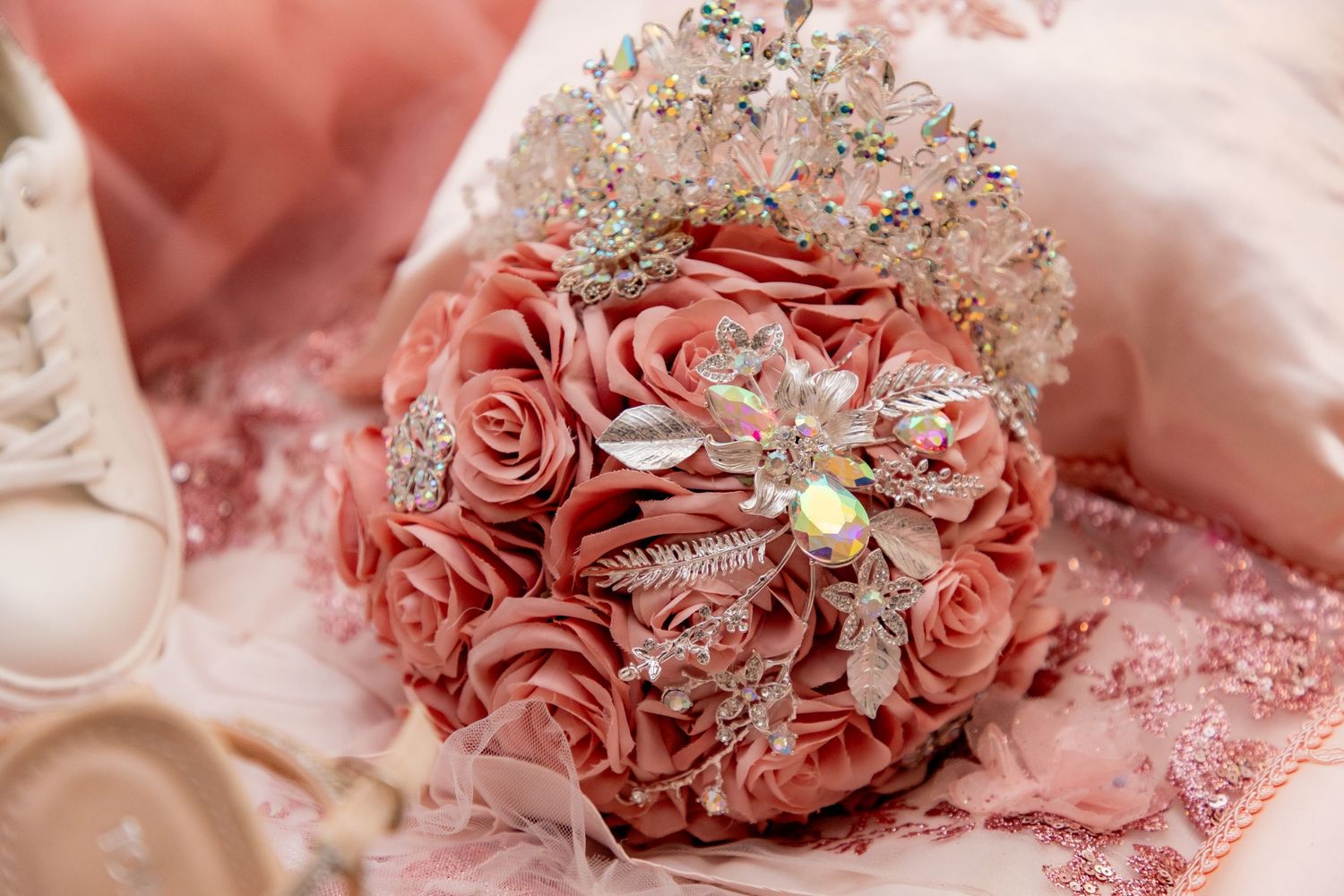 Ornate pink rose bouquet adorned with sparkling crystal brooches and tiara for quinceañera.