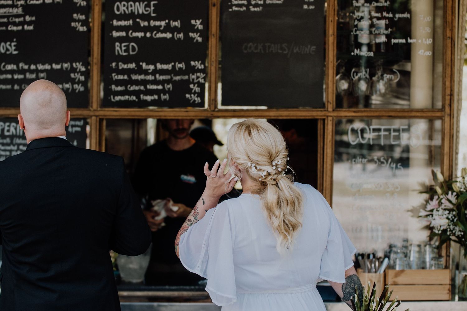 A rustic cafe interior with chalkboard menus and wooden furniture visible through glass windows.