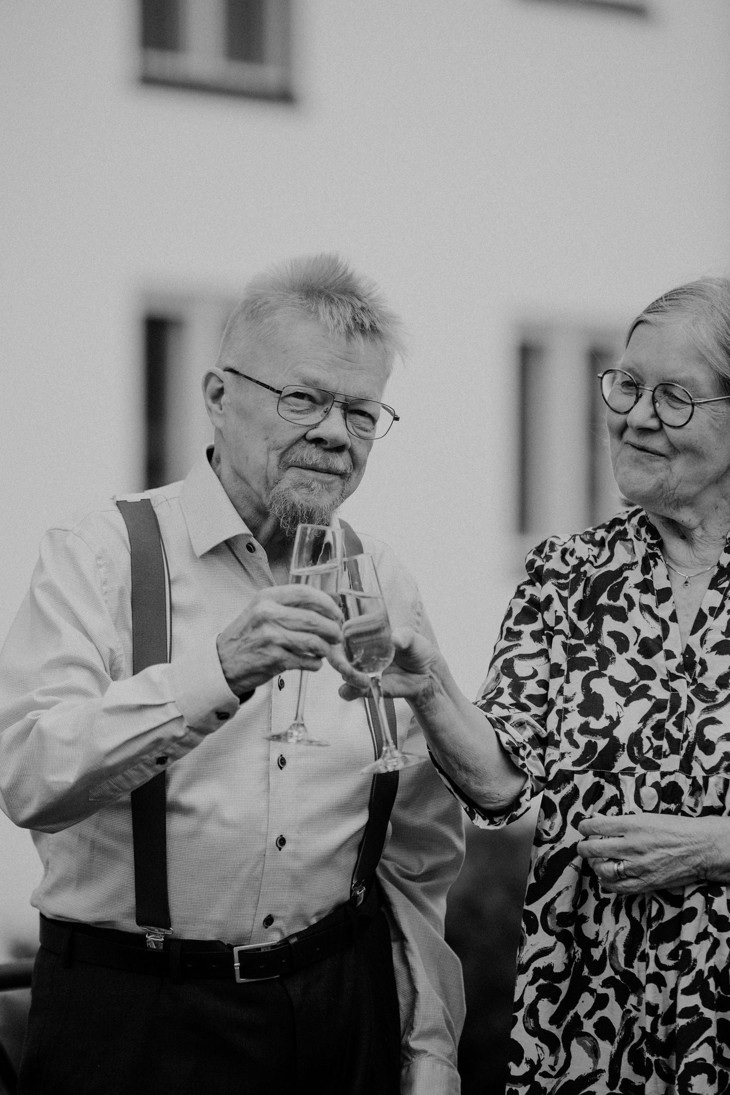 Black and white photo series showing an elderly couple sharing a drink together while smiling and laughing.