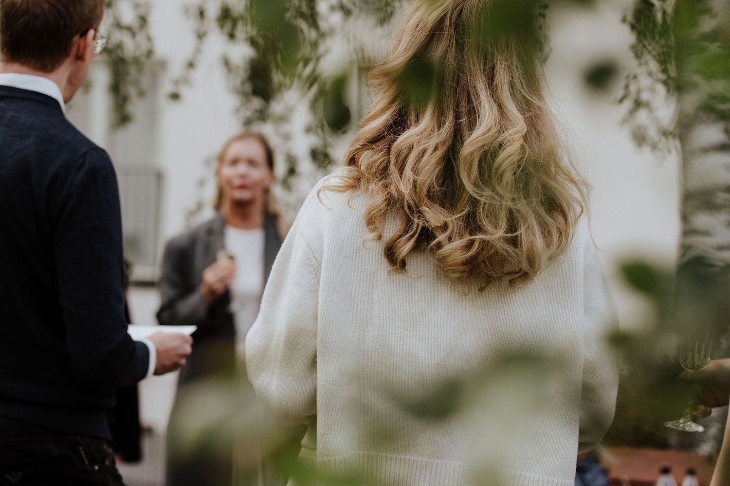 A couple embraces during an outdoor wedding ceremony surrounded by guests and greenery.