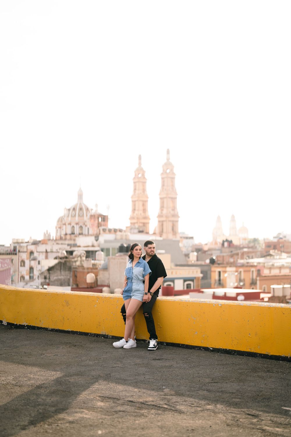 Couple embracing on a rooftop terrace with historic church towers visible in the background.
