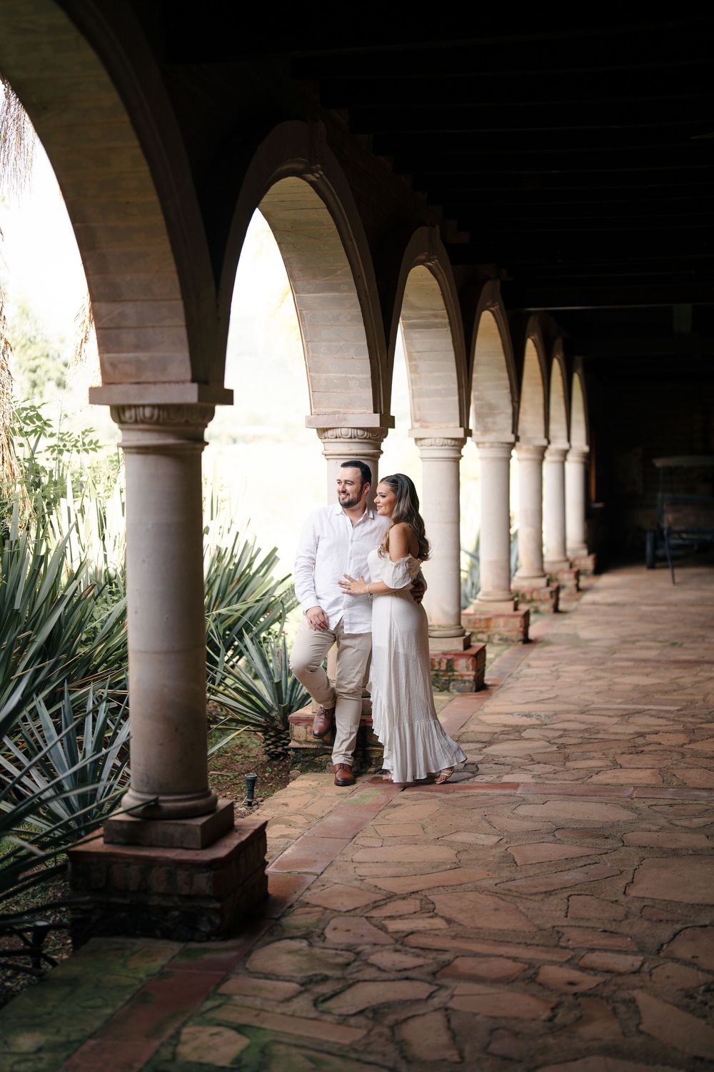 Couple sitting together in a beautiful Spanish colonial archway with agave plants.