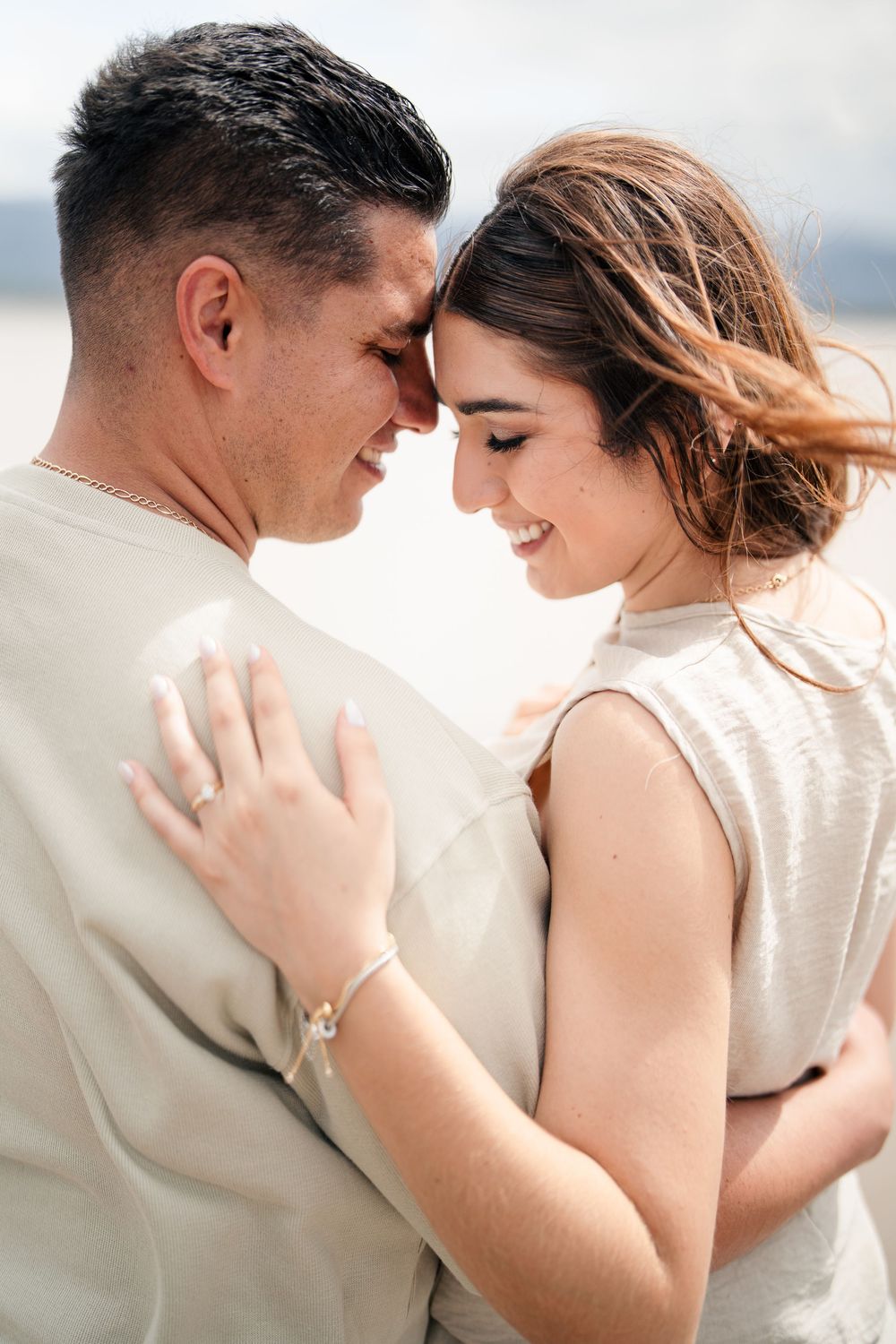 Intimate close-up of couple in neutral tones sharing tender moment on beach.