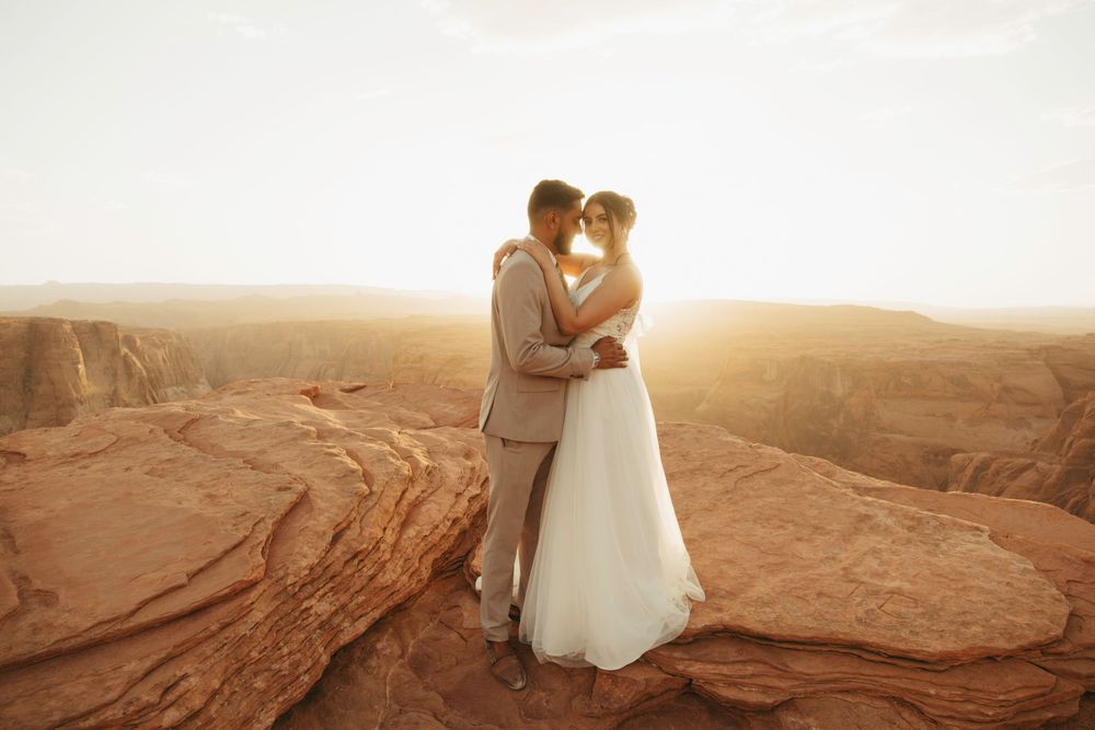 A couple embraces on desert cliffs during golden hour.
