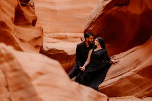 A couple shares an intimate moment within the curved walls of a red rock canyon.