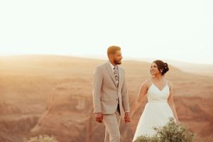 A couple in silhouette stands on red rocks against a dramatic sunset sky.