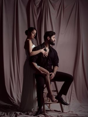 Dramatic black and white photo series showing two figures in artistic poses against a draped fabric backdrop.