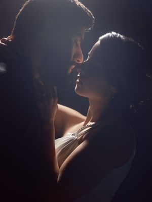 Artistic silhouette portrait of two figures in an intimate embrace with dramatic rim lighting creating a moody atmosphere.