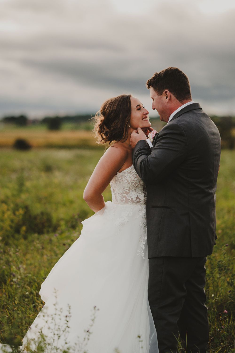 A tender moment between newlyweds in a golden field during sunset.