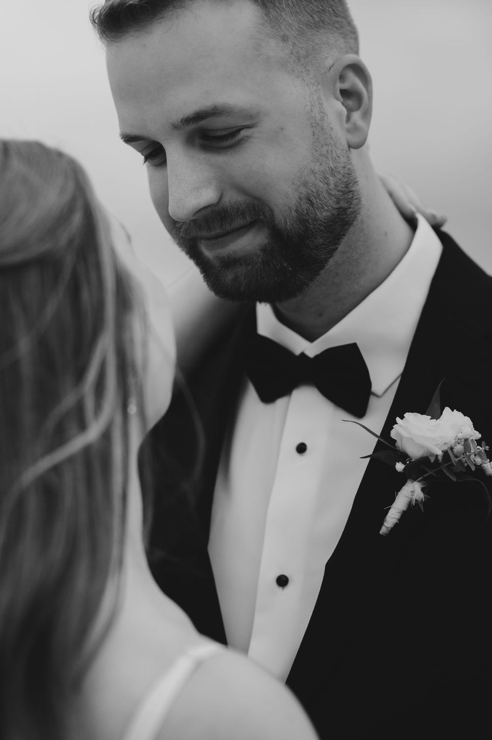 Intimate black and white wedding portrait with groom in classic tuxedo.