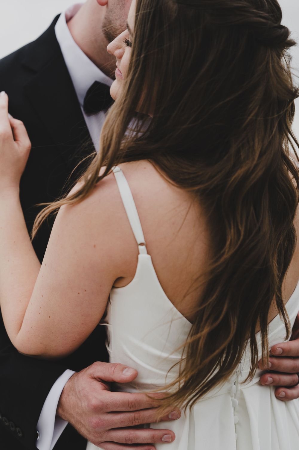 Intimate moment between newlyweds showing details of wedding attire.