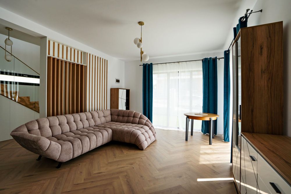 Modern living area with curved sectional sofa, wooden slat wall feature, and blue drapes.