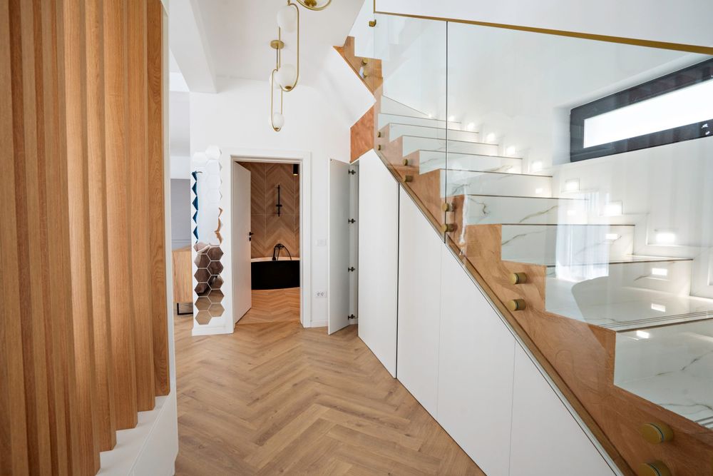 Modern wooden staircase with glass railing in a bright white interior shows elegant minimalist design.