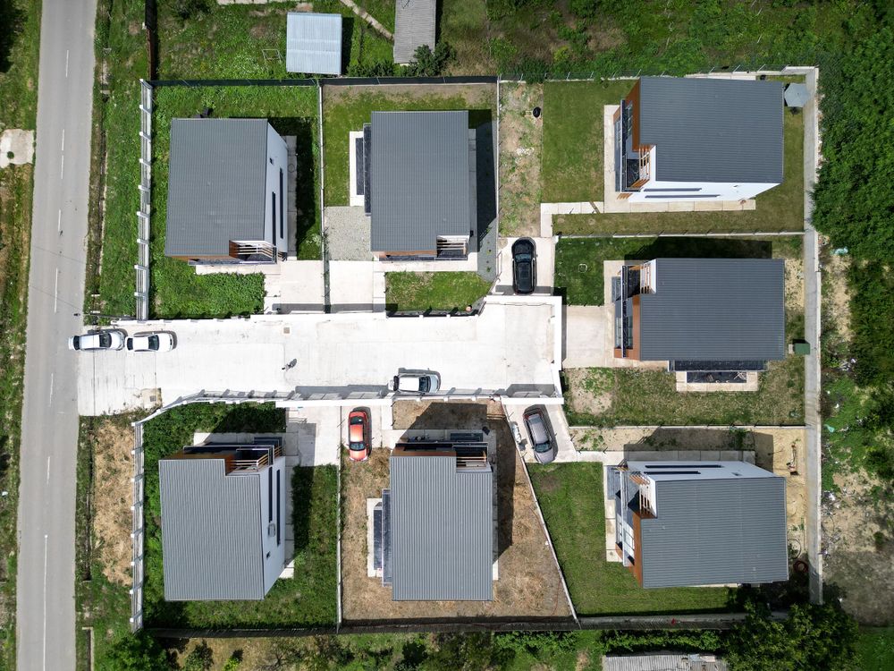 Aerial view of residential development showing multiple house plots and streets from above.
