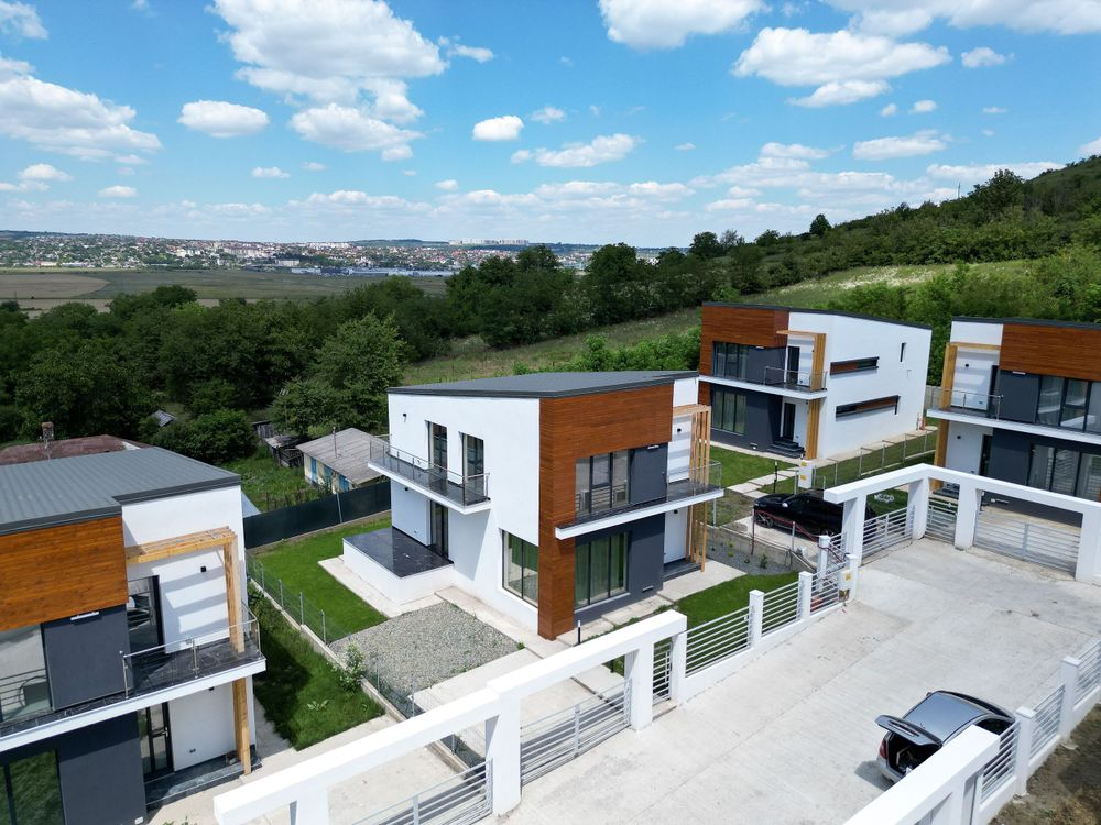 Modern luxury townhouses with wooden accents and white exterior viewed from a drone perspective.