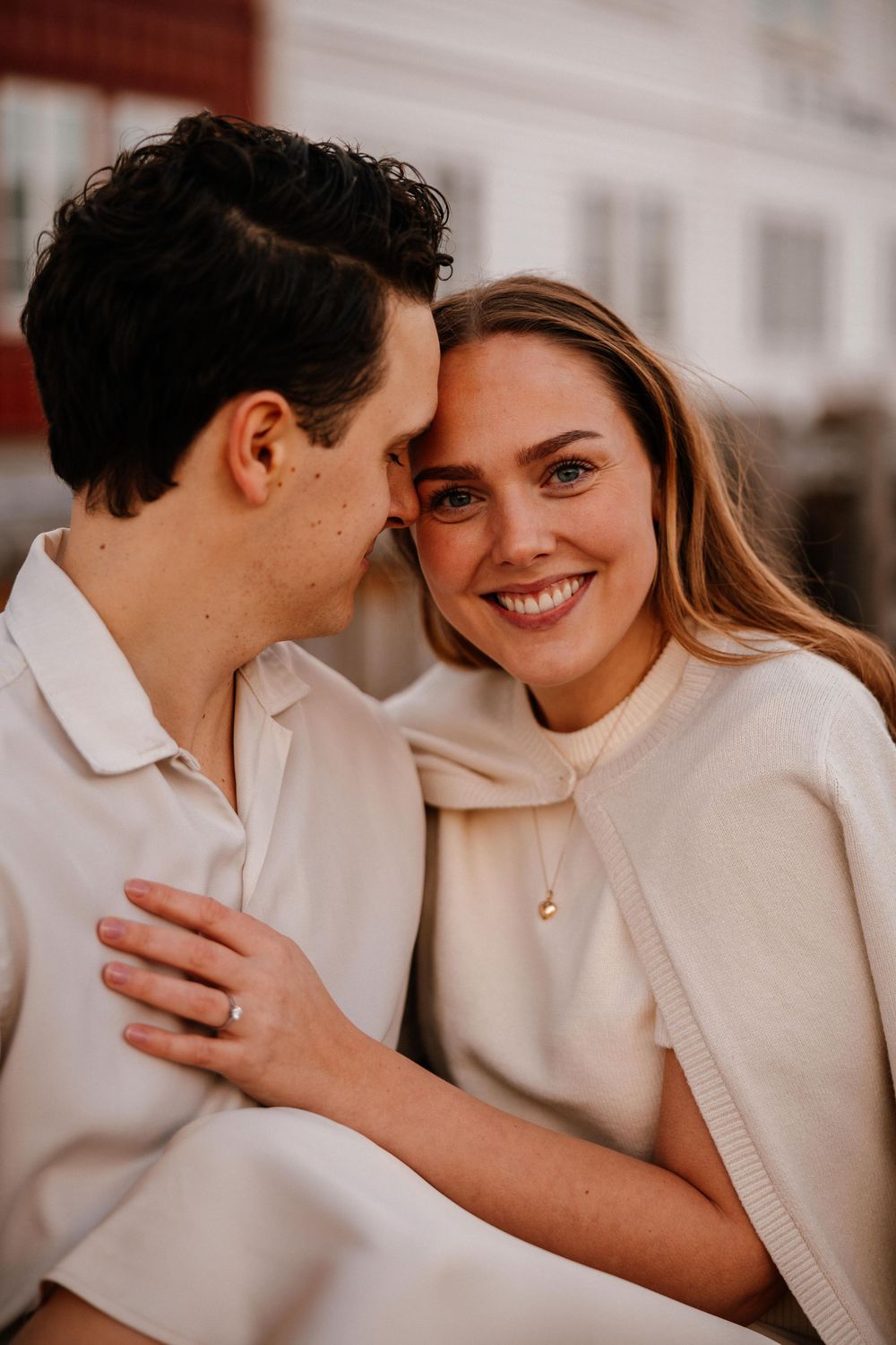 Romantic close-up portrait of a couple in cream colored sweaters smiling and embracing outdoors.