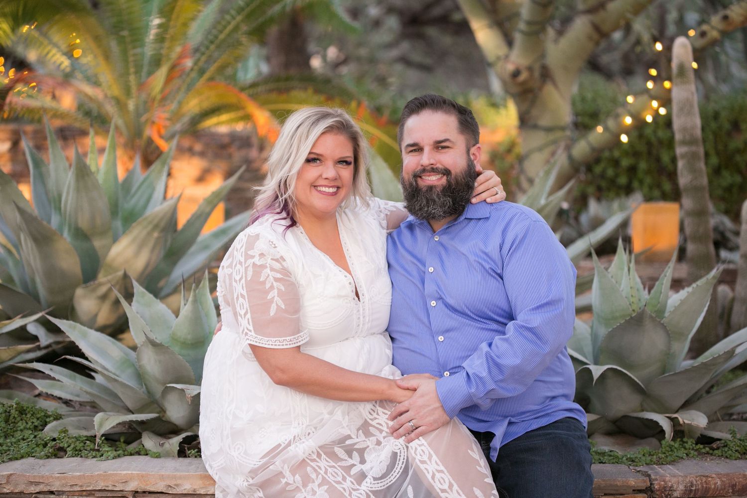 Smiling couple sitting together in desert garden with agave plants.
