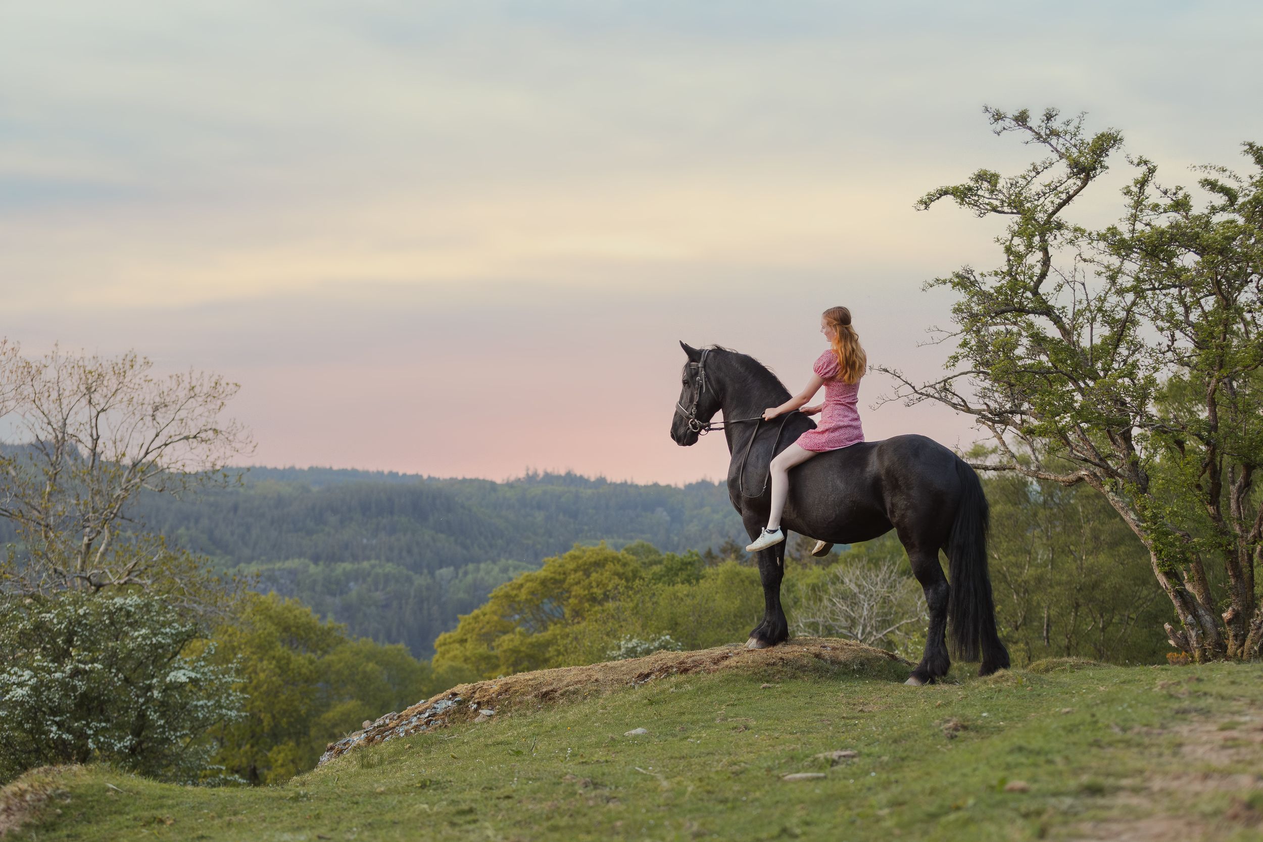 Horse and rider silhouetted against scenic mountain vista during sunset.