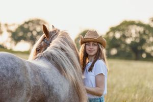 Cob horse and rider sharing a tender moment in a summer field.